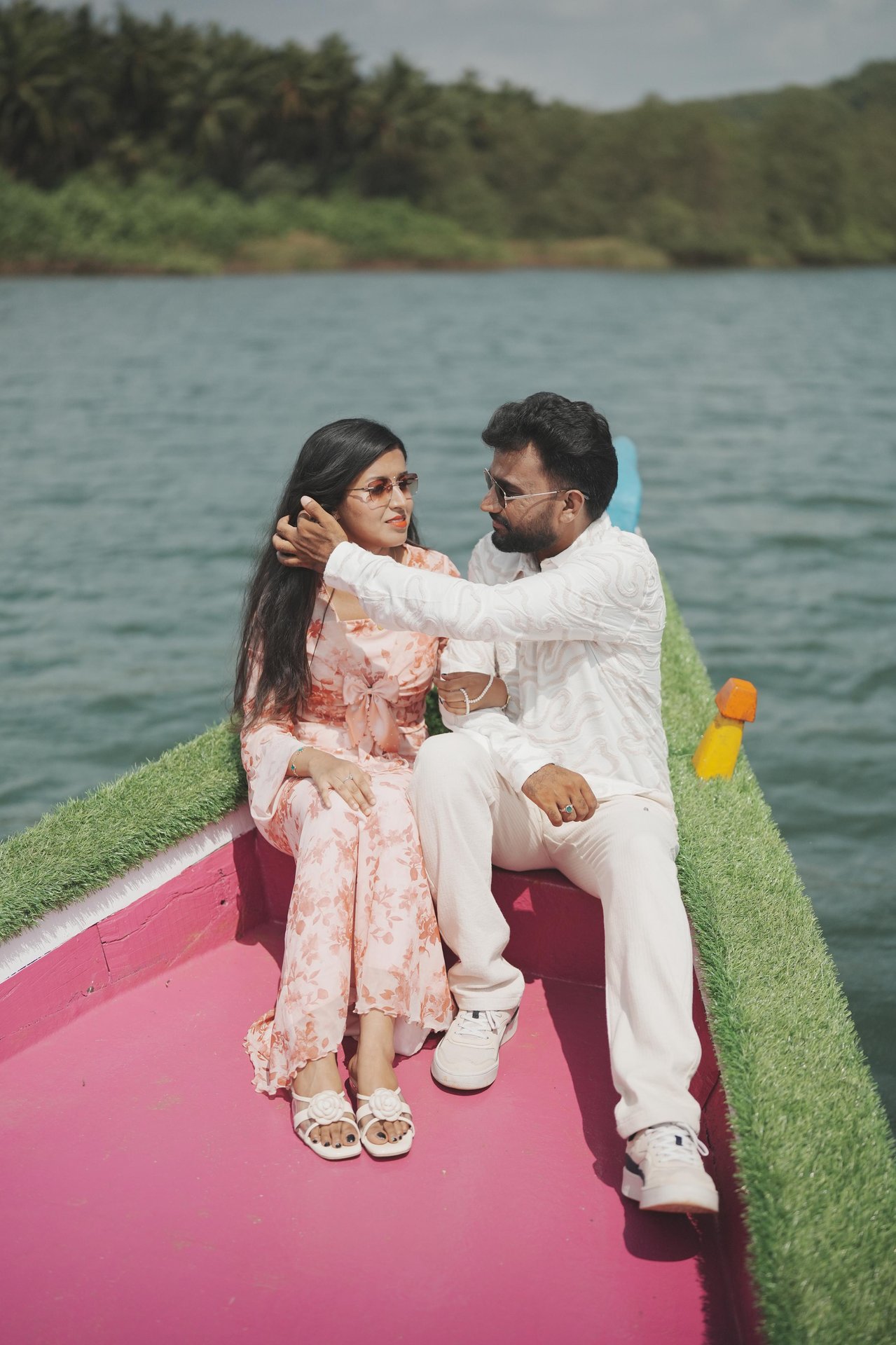 Purushotham and Nikitha sitting together on a pink boat